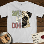 Saved by Dog Pug T-Shirt flat lay in White, featuring half a fawn Pug's face in distressed vintage screen print, a dark mask and one large round eye, cropped down the centerline beside bold stacked block lettering.