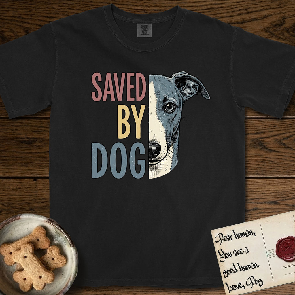 Saved by Dog Whippet T-Shirt flat lay in Black, featuring half a blue-grey Whippet's face in distressed vintage screen print, a folded rose ear and a large liquid eye, cropped down the centerline beside bold stacked block lettering.