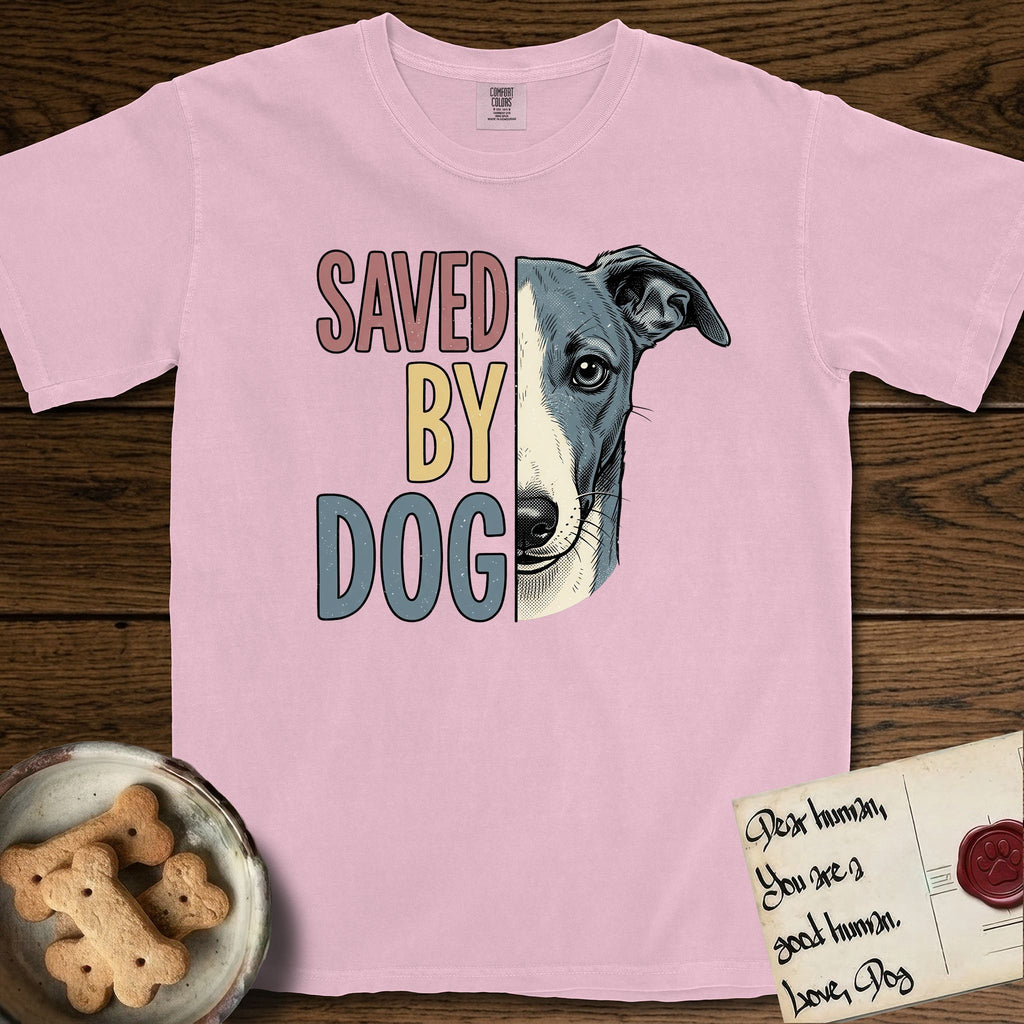 Saved by Dog Whippet T-Shirt flat lay in Blossom, featuring half a blue-grey Whippet's face in distressed vintage screen print, a folded rose ear and a large liquid eye, cropped down the centerline beside bold stacked block lettering.