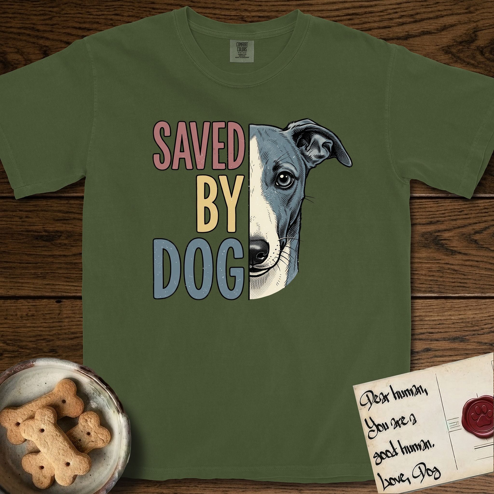 Saved by Dog Whippet T-Shirt flat lay in Hemp, featuring half a blue-grey Whippet's face in distressed vintage screen print, a folded rose ear and a large liquid eye, cropped down the centerline beside bold stacked block lettering.