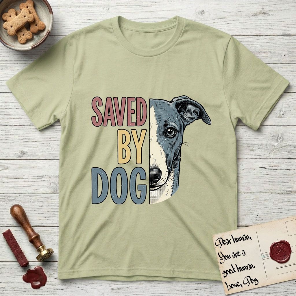 Saved by Dog Whippet T-Shirt flat lay in Pistachio, featuring half a blue-grey Whippet's face in distressed vintage screen print, a folded rose ear and a large liquid eye, cropped down the centerline beside bold stacked block lettering.