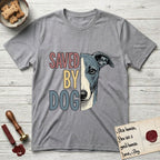 Saved by Dog Whippet T-Shirt flat lay in Sport Grey, featuring half a blue-grey Whippet's face in distressed vintage screen print, a folded rose ear and a large liquid eye, cropped down the centerline beside bold stacked block lettering.