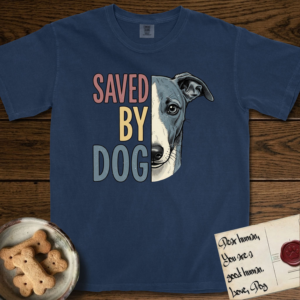 Saved by Dog Whippet T-Shirt flat lay in True Navy, featuring half a blue-grey Whippet's face in distressed vintage screen print, a folded rose ear and a large liquid eye, cropped down the centerline beside bold stacked block lettering.