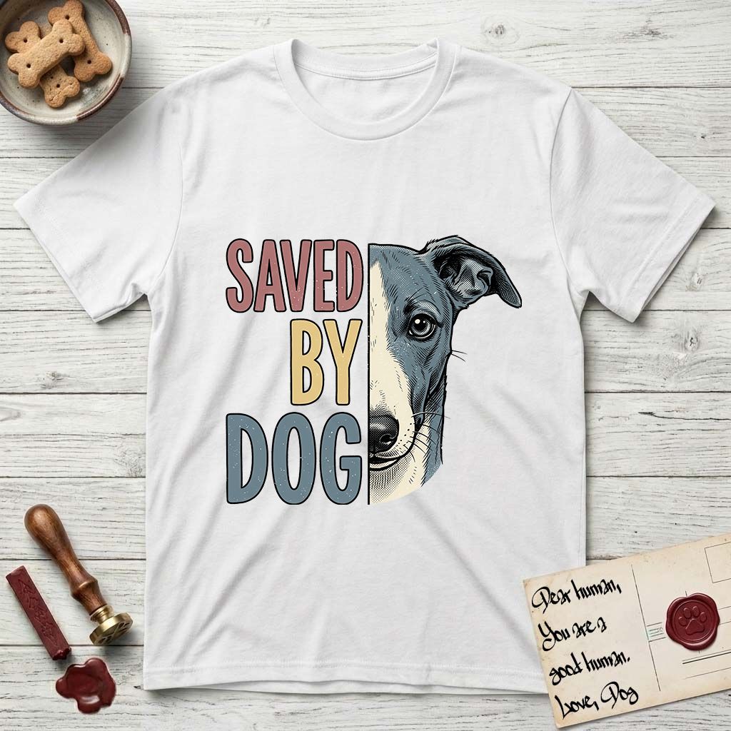 Saved by Dog Whippet T-Shirt flat lay in White, featuring half a blue-grey Whippet's face in distressed vintage screen print, a folded rose ear and a large liquid eye, cropped down the centerline beside bold stacked block lettering.
