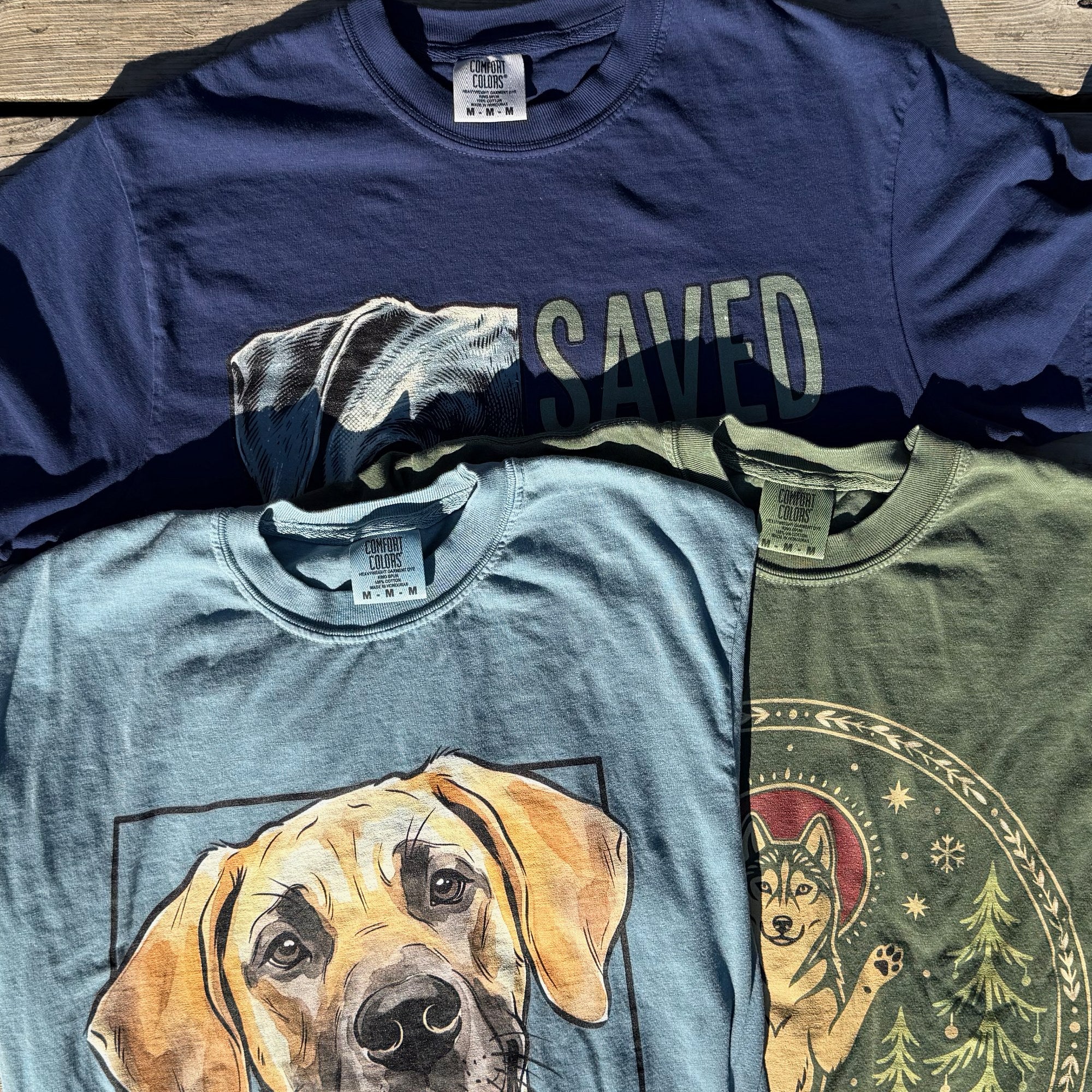 Three Dogma House shirts on Comfort Colors 1717 blanks, garment-dyed navy, blue and green, tags and collar seams showing