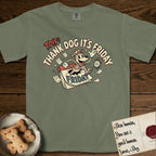 Thank Dog It's Friday T-Shirt flat lay in Sage, featuring a retro 1930s cartoon of a Dog bursting through a Friday calendar page, surrounded by musical notes, stars, and a clock, with retro display lettering reading TDIF.