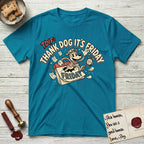 Thank Dog It's Friday T-Shirt flat lay in Tropical Blue, featuring a retro 1930s cartoon of a Dog bursting through a Friday calendar page, surrounded by musical notes, stars, and a clock, with retro display lettering reading TDIF.