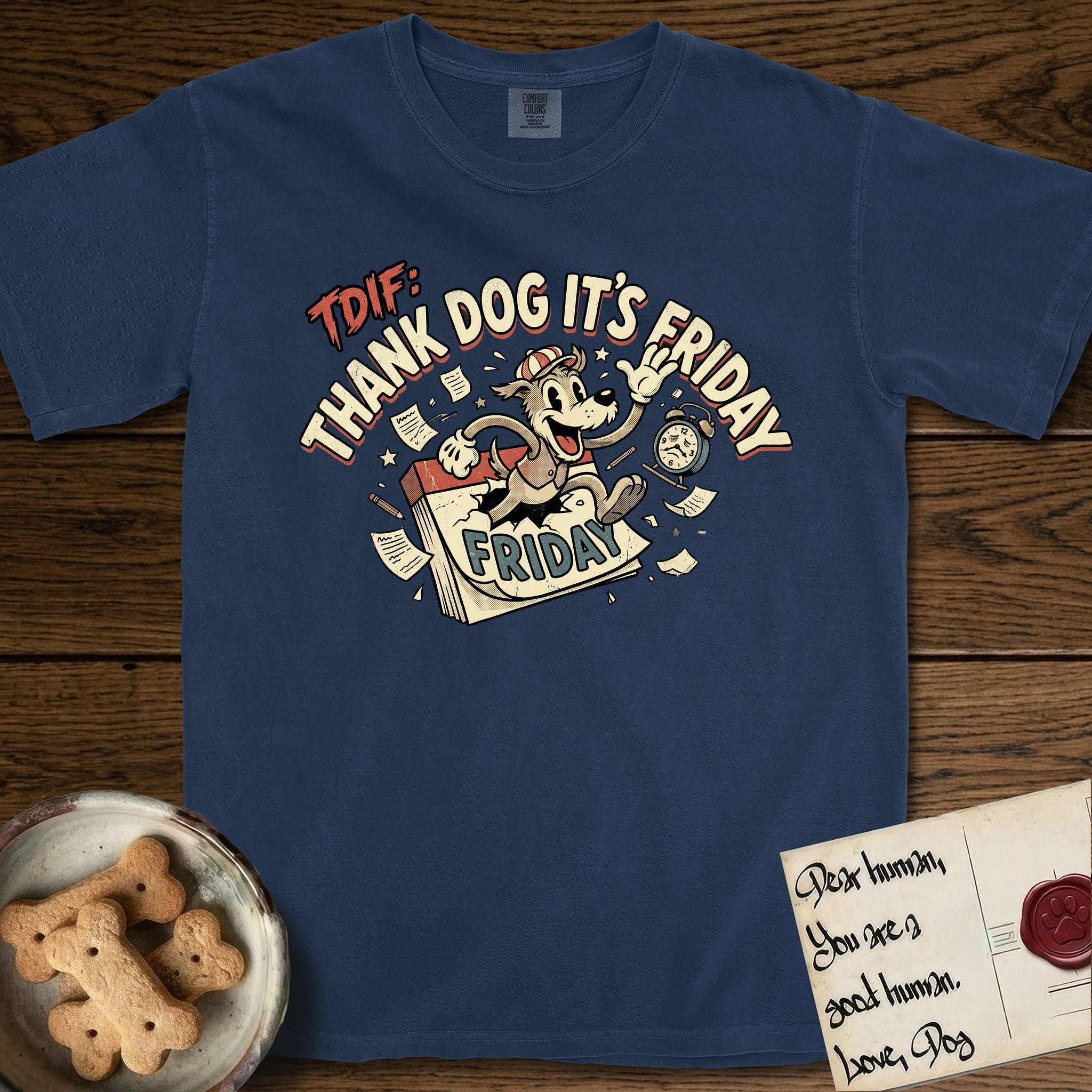 Thank Dog It's Friday T-Shirt flat lay in True Navy, featuring a retro 1930s cartoon of a Dog bursting through a Friday calendar page, surrounded by musical notes, stars, and a clock, with retro display lettering reading TDIF.