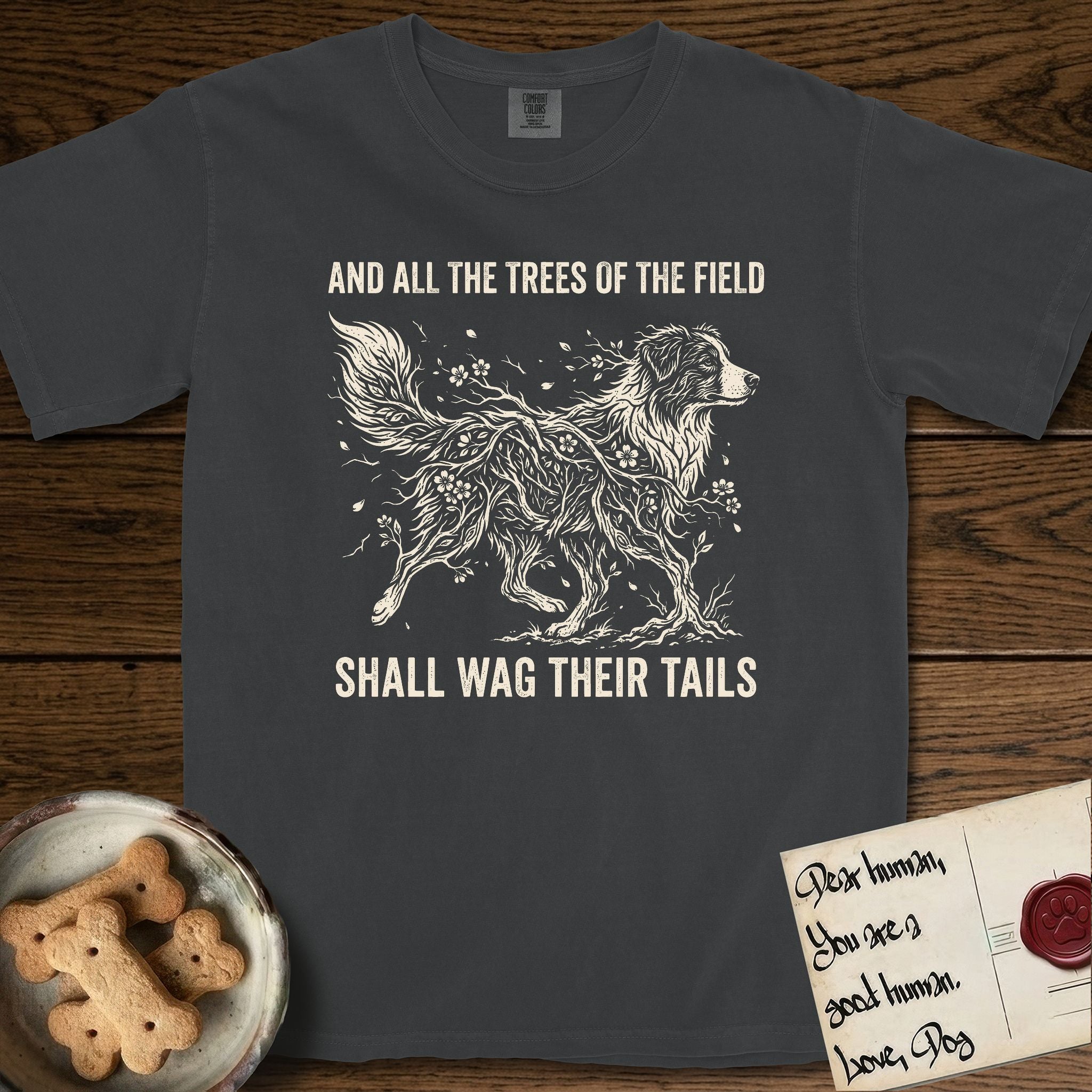 Trees of the Field Australian Shepherd T-Shirt flat lay in Graphite, featuring a vintage woodcut illustration of an Australian Shepherd formed of flowering cherry branches, mid-stride, with the words And All the Trees of the Field Shall Wag Their Tails.