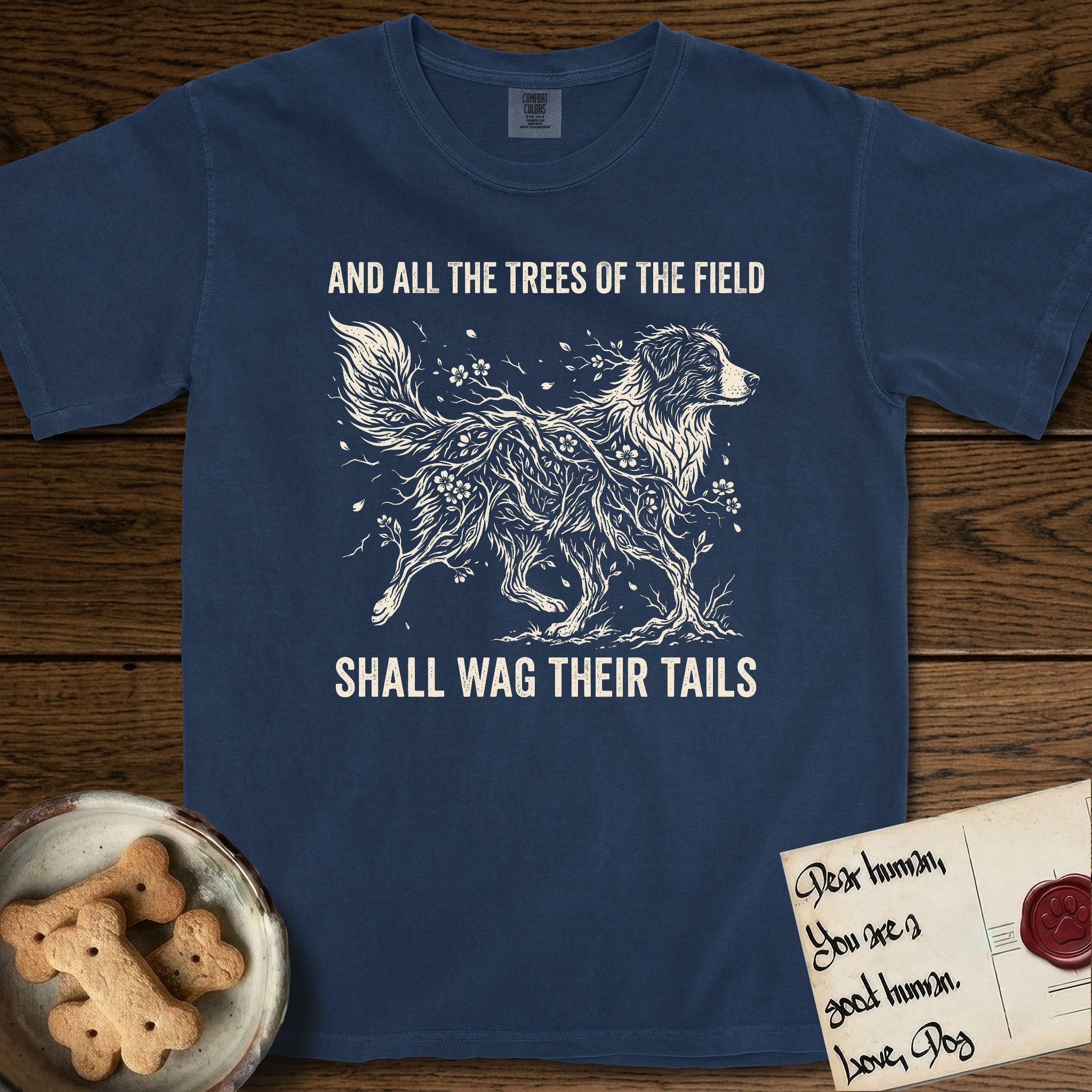 Trees of the Field Australian Shepherd T-Shirt flat lay in True Navy, featuring a vintage woodcut illustration of an Australian Shepherd formed of flowering cherry branches, mid-stride, with the words And All the Trees of the Field Shall Wag Their Tails.