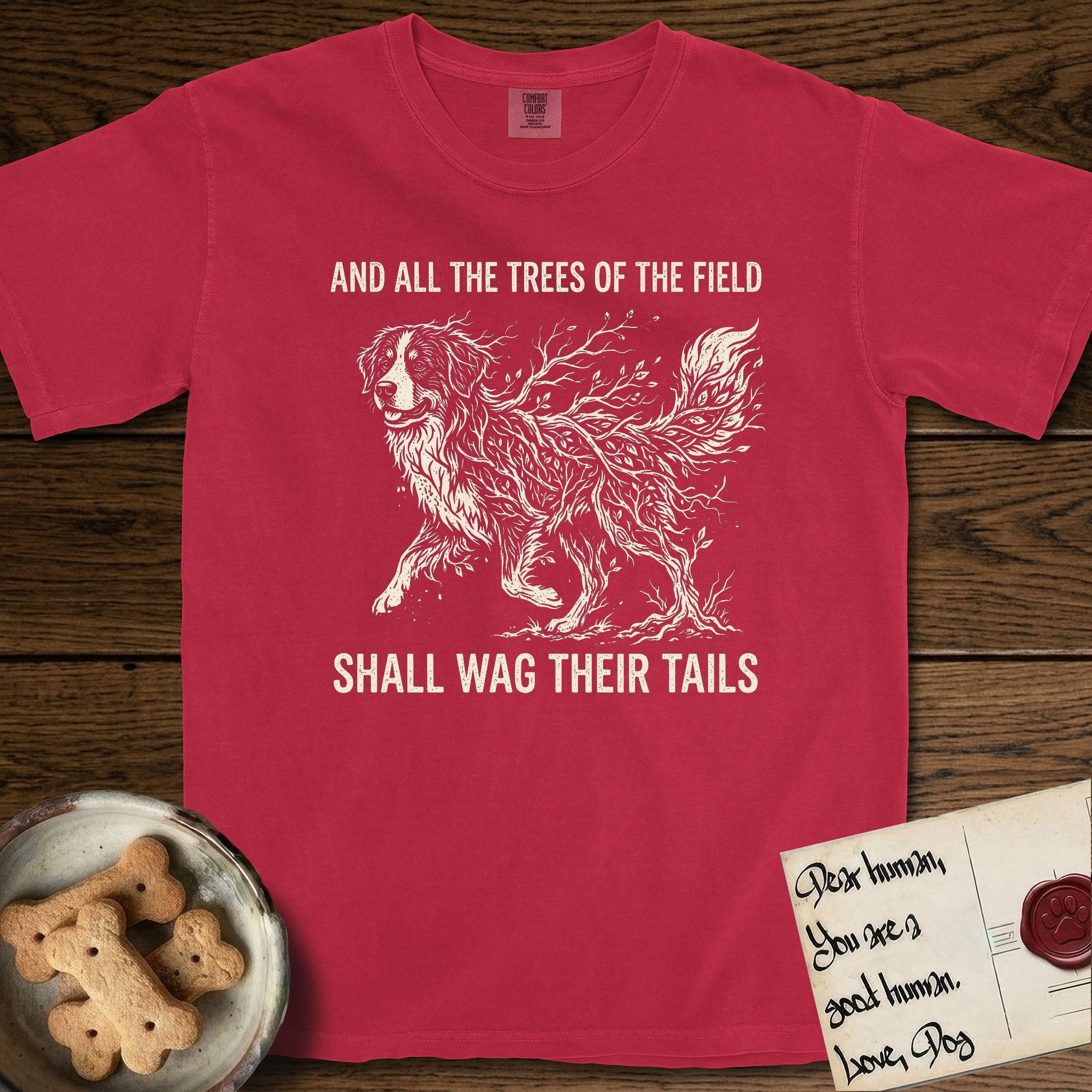 Trees of the Field Bernese Mountain Dog T-Shirt flat lay in Red, featuring a vintage woodcut illustration of a Bernese Mountain Dog formed of bare windswept winter branches, mid-stride, with the words And All the Trees of the Field Shall Wag Their Tails.