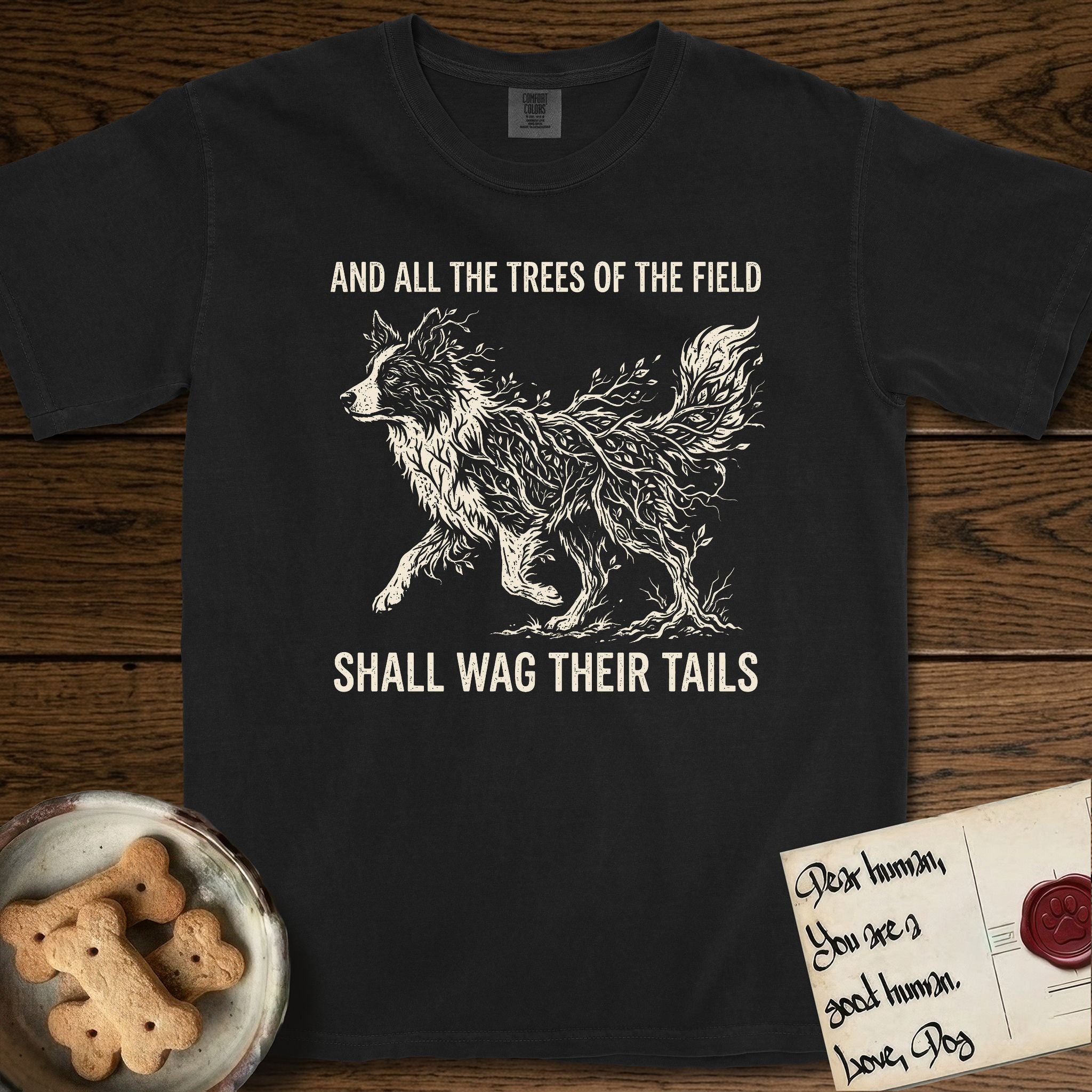 Trees of the Field Border Collie T-Shirt flat lay in Black, featuring a vintage woodcut illustration of a Border Collie formed of quaking aspen branches, mid-stride, with the words And All the Trees of the Field Shall Wag Their Tails.