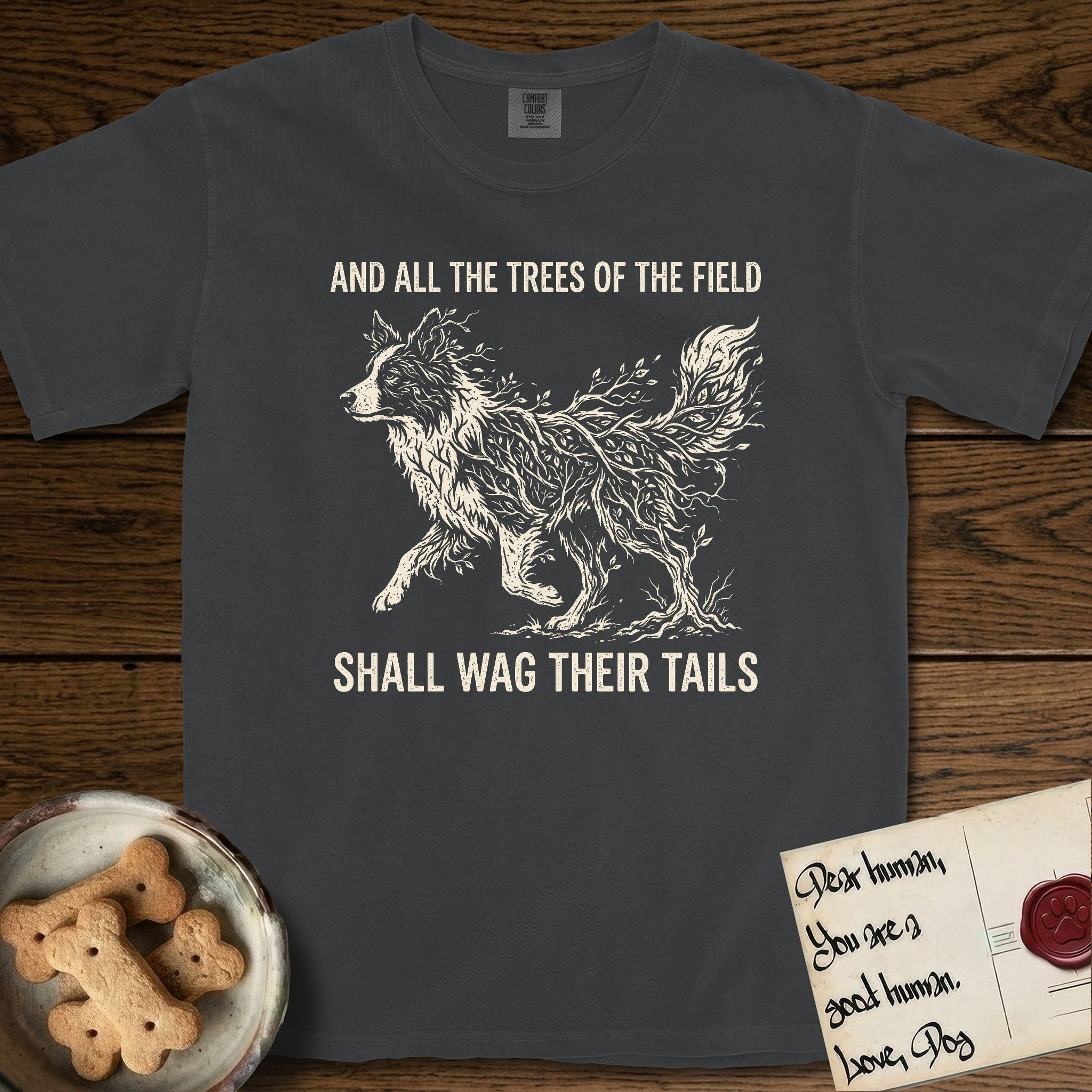 Trees of the Field Border Collie T-Shirt flat lay in Graphite, featuring a vintage woodcut illustration of a Border Collie formed of quaking aspen branches, mid-stride, with the words And All the Trees of the Field Shall Wag Their Tails.