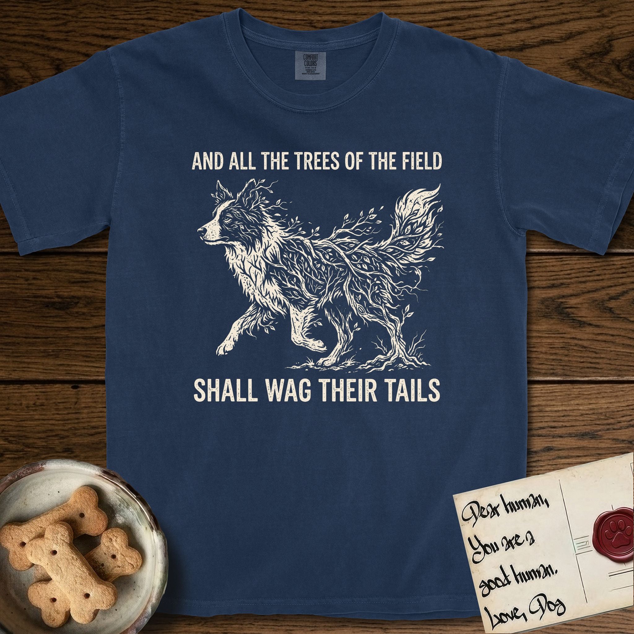 Trees of the Field Border Collie T-Shirt flat lay in True Navy, featuring a vintage woodcut illustration of a Border Collie formed of quaking aspen branches, mid-stride, with the words And All the Trees of the Field Shall Wag Their Tails.