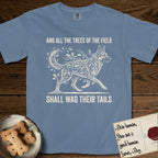Trees of the Field German Shepherd T-Shirt flat lay in Blue Jean, featuring a vintage woodcut illustration of a German Shepherd formed of oak branches with acorns, mid-stride, with the words And All the Trees of the Field Shall Wag Their Tails.