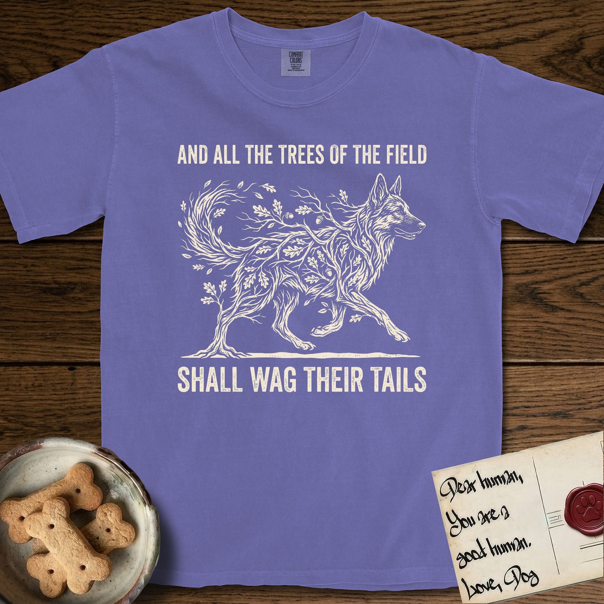 Trees of the Field German Shepherd T-Shirt flat lay in Violet, featuring a vintage woodcut illustration of a German Shepherd formed of oak branches with acorns, mid-stride, with the words And All the Trees of the Field Shall Wag Their Tails.