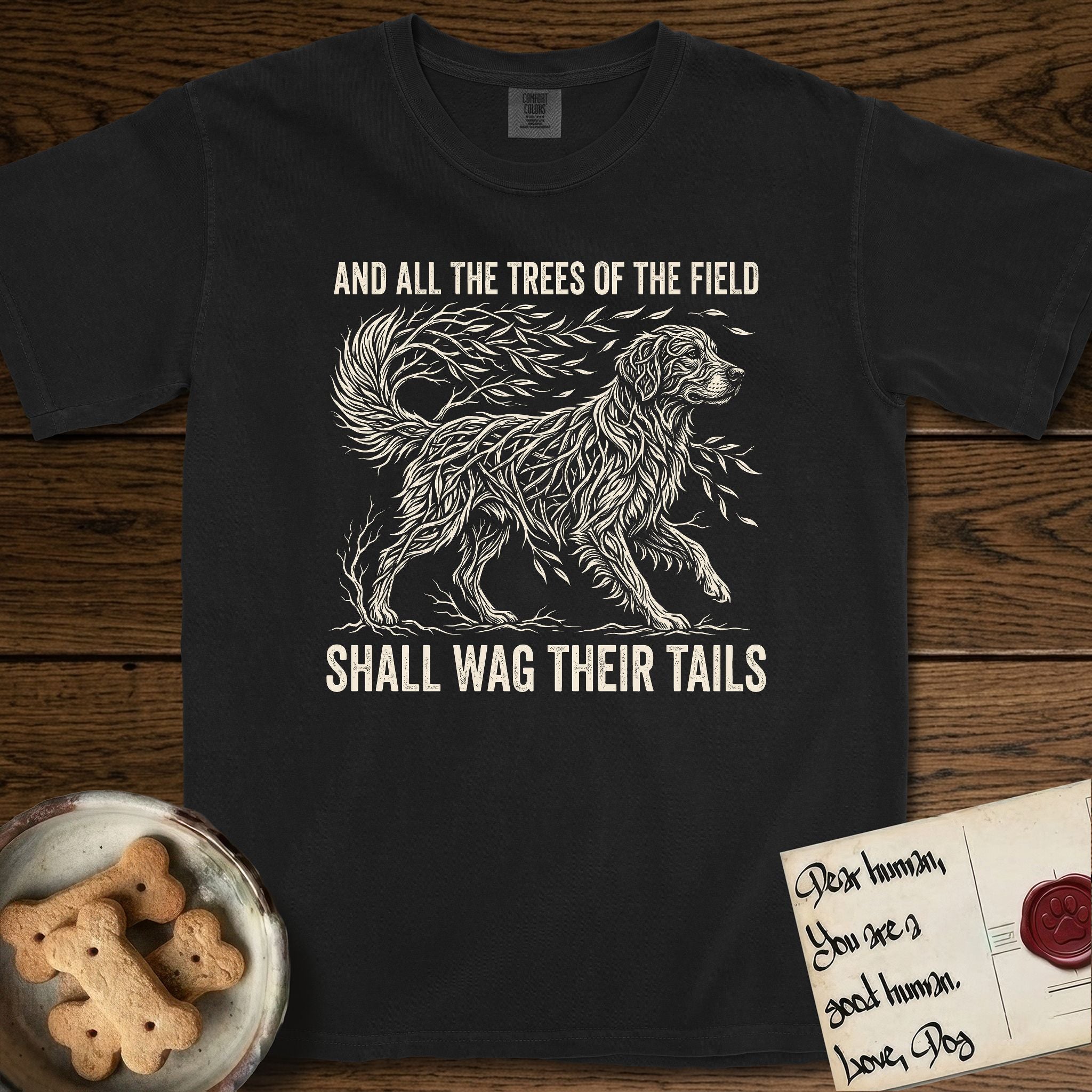 Trees of the Field Golden Retriever T-Shirt flat lay in Black, featuring a vintage woodcut illustration of a Golden Retriever formed of flowing willow branches, mid-stride, with the words And All the Trees of the Field Shall Wag Their Tails.