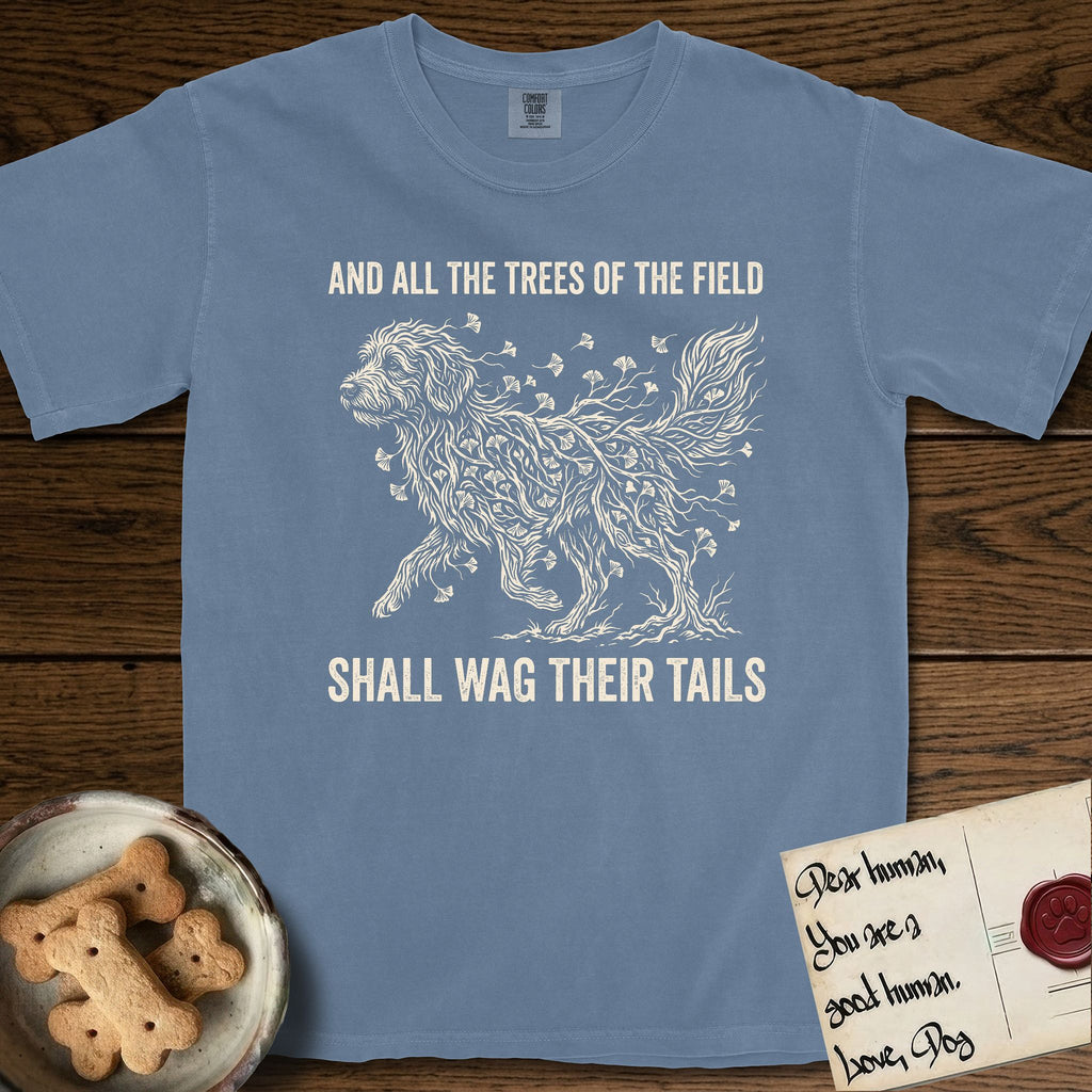 Trees of the Field Goldendoodle T-Shirt flat lay in Blue Jean, featuring a vintage woodcut illustration of a Goldendoodle formed of ginkgo branches with fan-shaped leaves, mid-stride, with the words And All the Trees of the Field Shall Wag Their Tails.