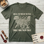 Trees of the Field Goldendoodle T-Shirt flat lay in Heather Military Green, featuring a vintage woodcut illustration of a Goldendoodle formed of ginkgo branches with fan-shaped leaves, mid-stride, with the words And All the Trees of the Field Shall Wag Their Tails.
