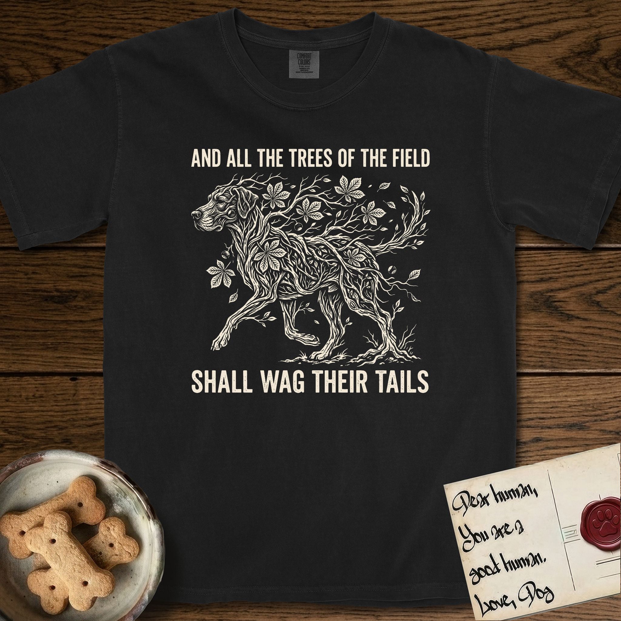 Trees of the Field Great Dane T-Shirt flat lay in Black, featuring a vintage woodcut illustration of a Great Dane formed of horse chestnut branches and leaves, mid-stride, with the words And All the Trees of the Field Shall Wag Their Tails.