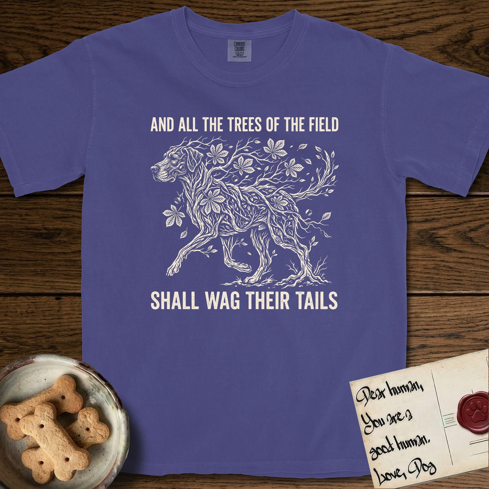 Trees of the Field Great Dane T-Shirt flat lay in Grape, featuring a vintage woodcut illustration of a Great Dane formed of horse chestnut branches and leaves, mid-stride, with the words And All the Trees of the Field Shall Wag Their Tails.