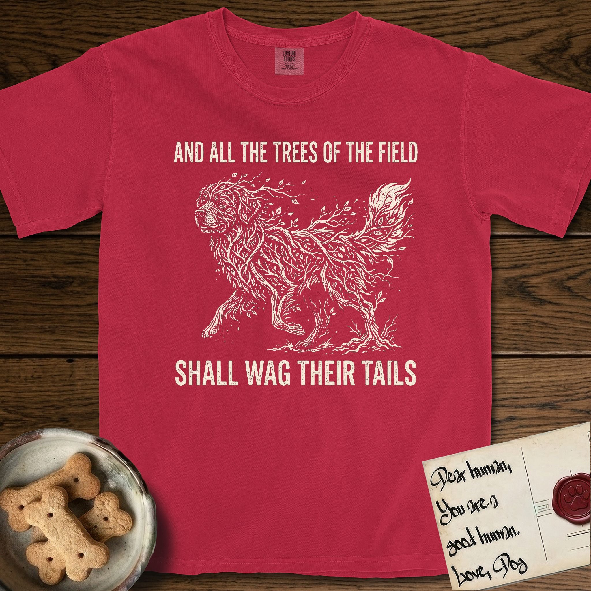 Trees of the Field Newfoundland T-Shirt flat lay in Red, featuring a vintage woodcut illustration of a Newfoundland formed of linden branches in full leaf, mid-stride, with the words And All the Trees of the Field Shall Wag Their Tails.