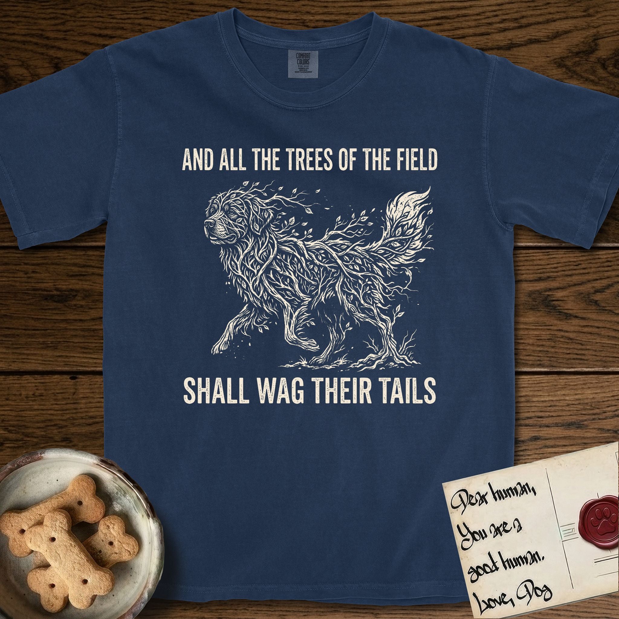 Trees of the Field Newfoundland T-Shirt flat lay in True Navy, featuring a vintage woodcut illustration of a Newfoundland formed of linden branches in full leaf, mid-stride, with the words And All the Trees of the Field Shall Wag Their Tails.