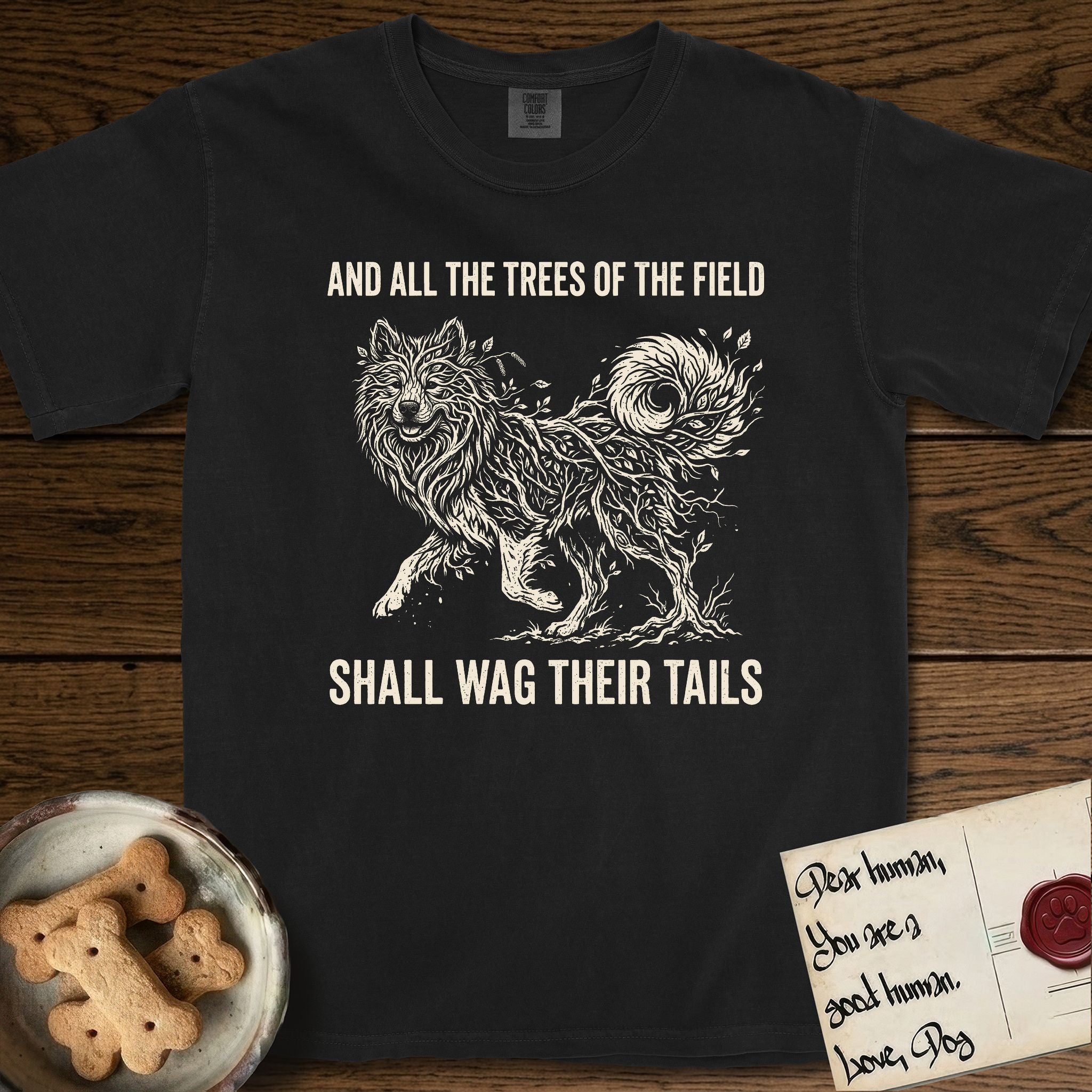Trees of the Field Samoyed T-Shirt flat lay in Black, featuring a vintage woodcut illustration of a Samoyed formed of white birch branches with catkins, mid-stride, with the words And All the Trees of the Field Shall Wag Their Tails.