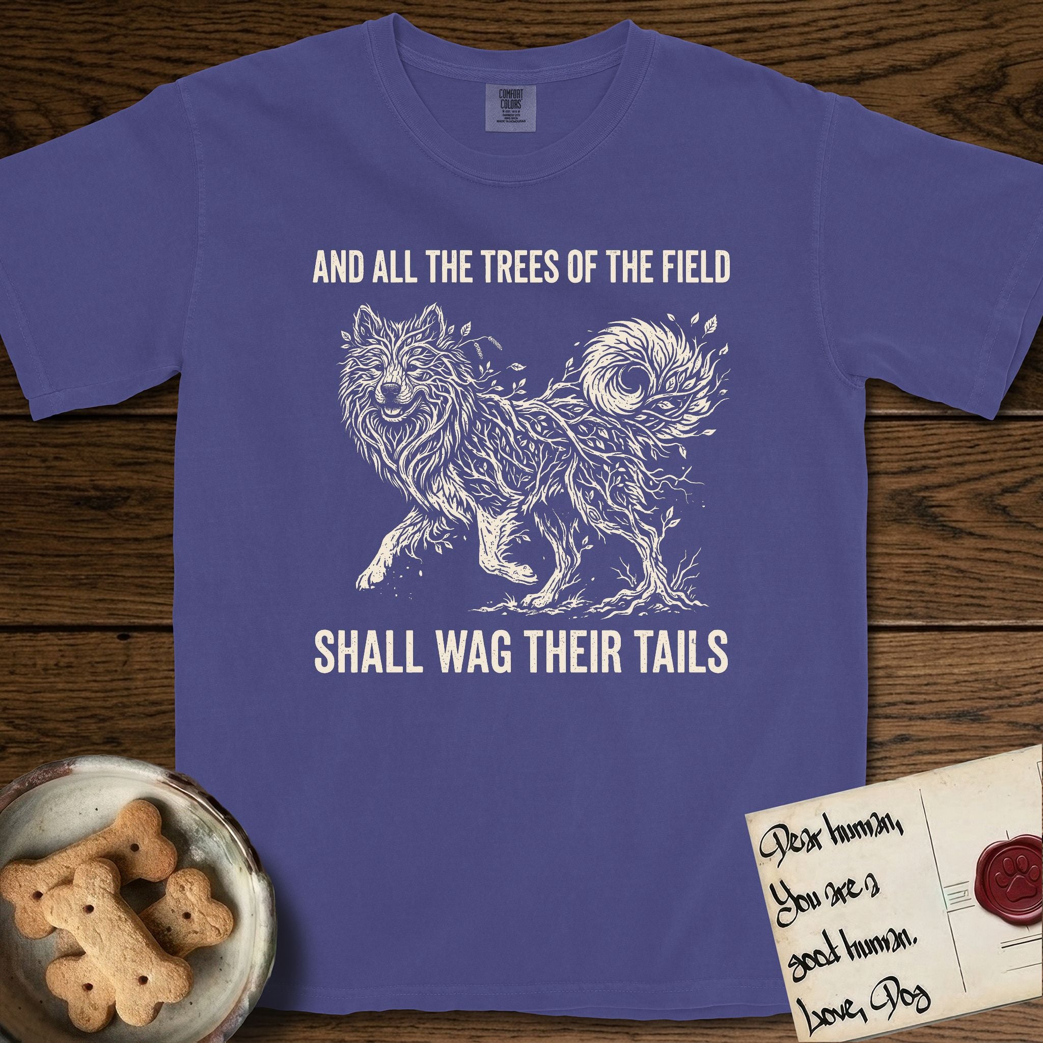 Trees of the Field Samoyed T-Shirt flat lay in Grape, featuring a vintage woodcut illustration of a Samoyed formed of white birch branches with catkins, mid-stride, with the words And All the Trees of the Field Shall Wag Their Tails.