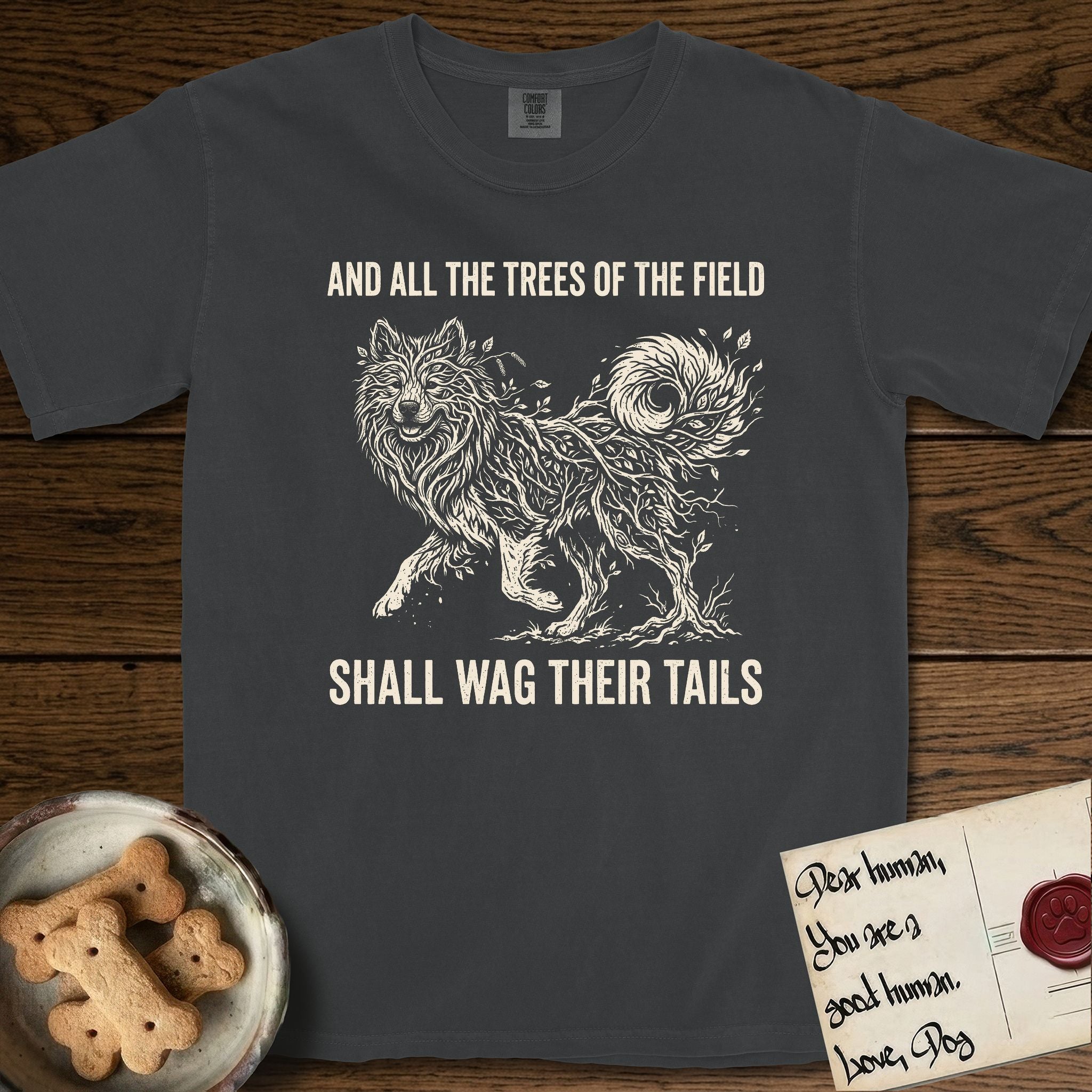 Trees of the Field Samoyed T-Shirt flat lay in Graphite, featuring a vintage woodcut illustration of a Samoyed formed of white birch branches with catkins, mid-stride, with the words And All the Trees of the Field Shall Wag Their Tails.