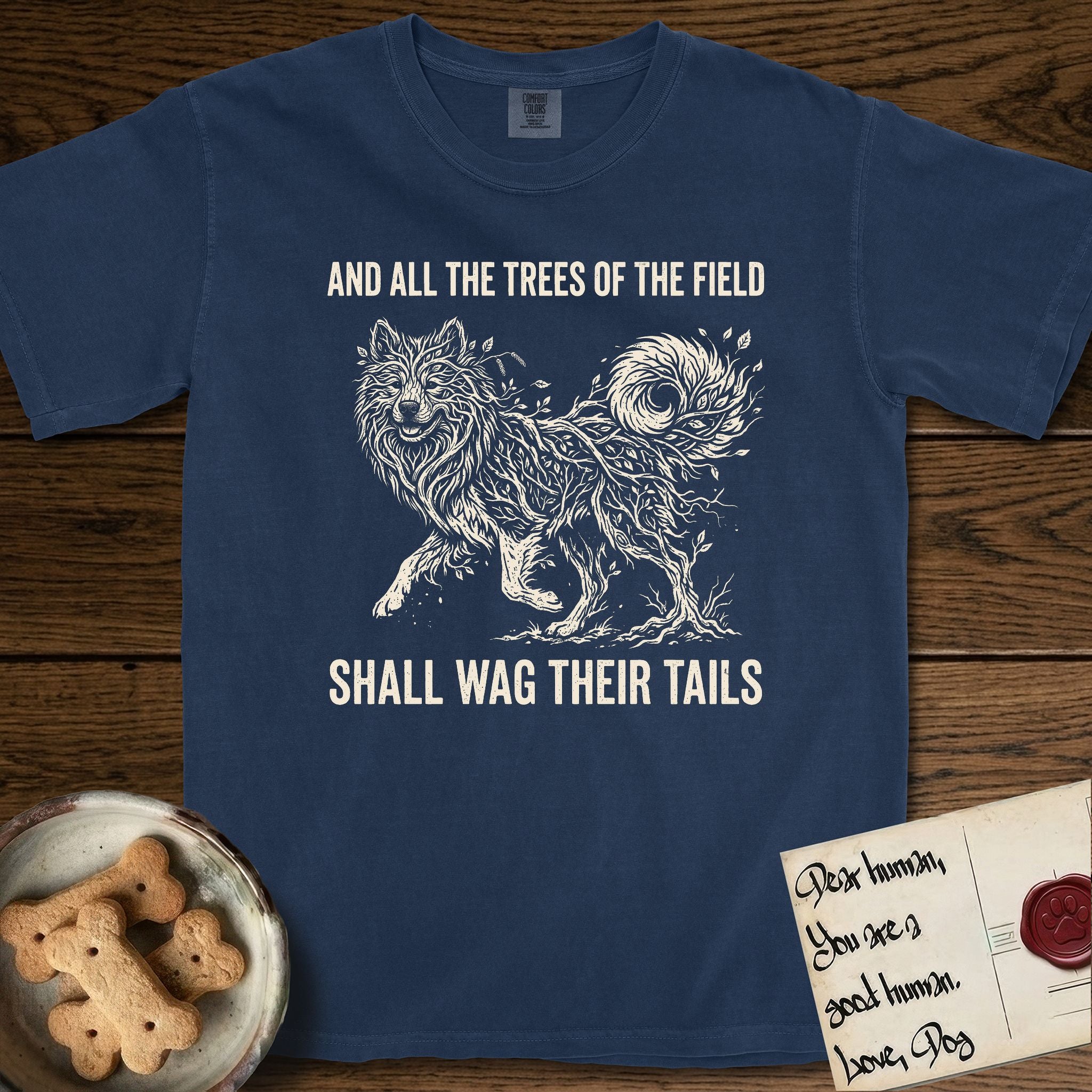 Trees of the Field Samoyed T-Shirt flat lay in True Navy, featuring a vintage woodcut illustration of a Samoyed formed of white birch branches with catkins, mid-stride, with the words And All the Trees of the Field Shall Wag Their Tails.