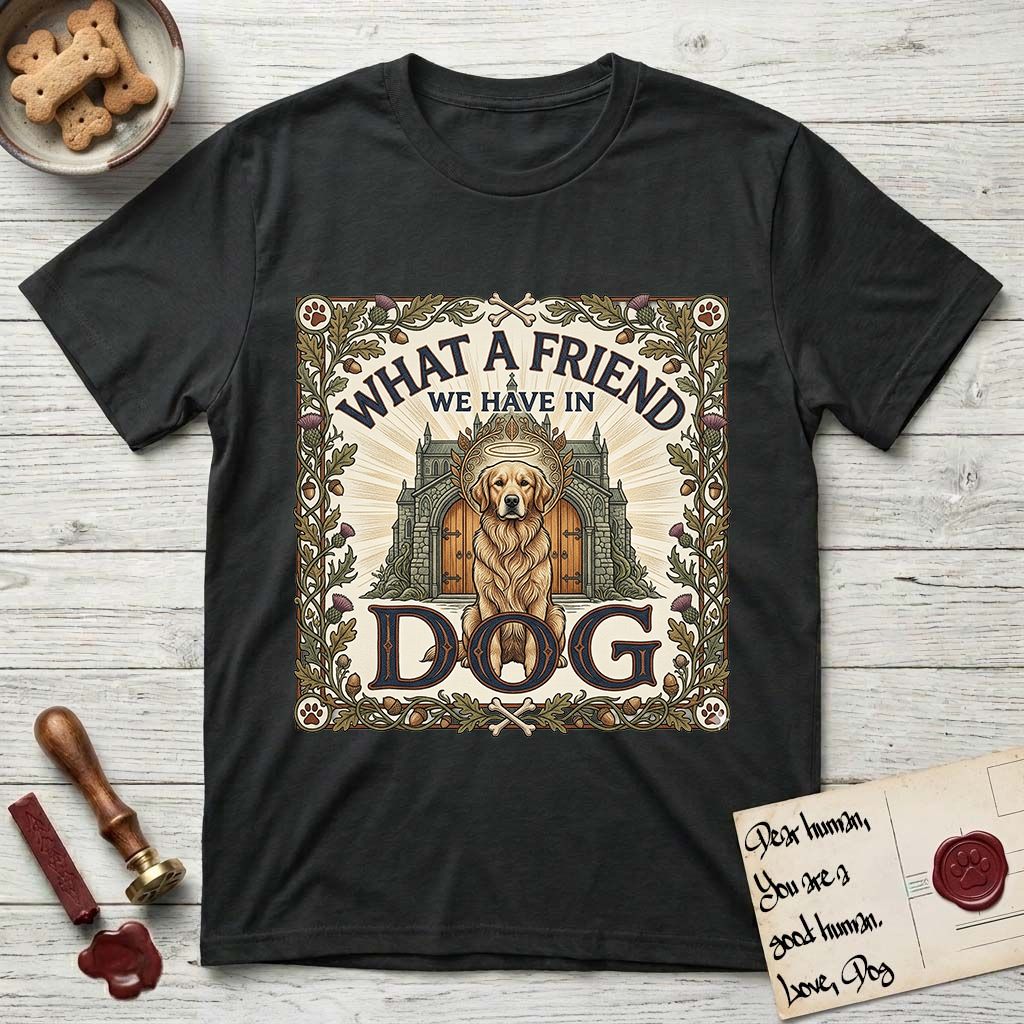 What a Friend We Have in Dog T-Shirt flat lay in Black, featuring an Arts and Crafts tapestry illustration of a haloed Golden Retriever seated before a monastery, framed by an oak-leaf, acorn, and thistle border, with the word DOG below.