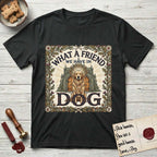 What a Friend We Have in Dog T-Shirt flat lay in Black, featuring an Arts and Crafts tapestry illustration of a haloed Golden Retriever seated before a monastery, framed by an oak-leaf, acorn, and thistle border, with the word DOG below.