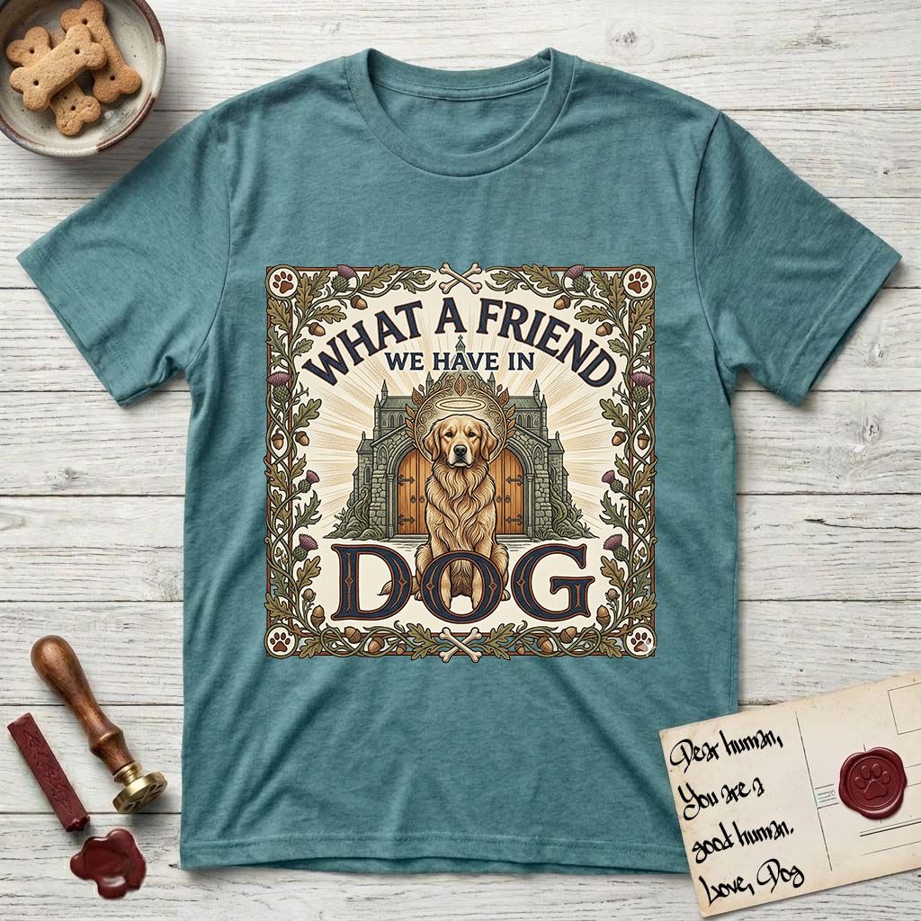 What a Friend We Have in Dog T-Shirt flat lay in Heather Galapagos Blue, featuring an Arts and Crafts tapestry illustration of a haloed Golden Retriever seated before a monastery, framed by an oak-leaf, acorn, and thistle border, with the word DOG below.