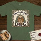 What a Friend We Have in Dog T-Shirt flat lay in Moss, featuring an Arts and Crafts tapestry illustration of a haloed Golden Retriever seated before a monastery, framed by an oak-leaf, acorn, and thistle border, with the word DOG below.
