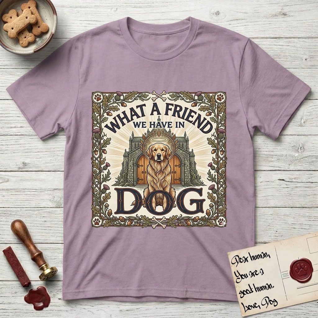 What a Friend We Have in Dog T-Shirt flat lay in Paragon, featuring an Arts and Crafts tapestry illustration of a haloed Golden Retriever seated before a monastery, framed by an oak-leaf, acorn, and thistle border, with the word DOG below.