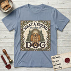 What a Friend We Have in Dog T-Shirt flat lay in Stone Blue, featuring an Arts and Crafts tapestry illustration of a haloed Golden Retriever seated before a monastery, framed by an oak-leaf, acorn, and thistle border, with the word DOG below.