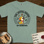 The Joyful Sound of Barking T-Shirt flat lay in Bay, featuring a flat vector cartoon emblem of a happy puppy with lifted ears surrounded by musical notes, ringed by the words The Joyful Sound of Barking.