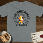 The Joyful Sound of Barking T-Shirt flat lay in Granite, featuring a flat vector cartoon emblem of a happy puppy with lifted ears surrounded by musical notes, ringed by the words The Joyful Sound of Barking.