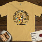 The Joyful Sound of Barking T-Shirt flat lay in Mustard, featuring a flat vector cartoon emblem of a happy puppy with lifted ears surrounded by musical notes, ringed by the words The Joyful Sound of Barking.