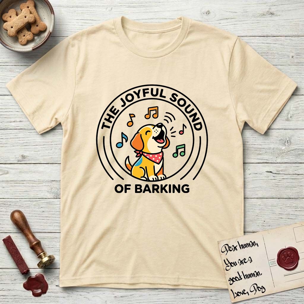The Joyful Sound of Barking T-Shirt flat lay in Natural, featuring a flat vector cartoon emblem of a happy puppy with lifted ears surrounded by musical notes, ringed by the words The Joyful Sound of Barking.