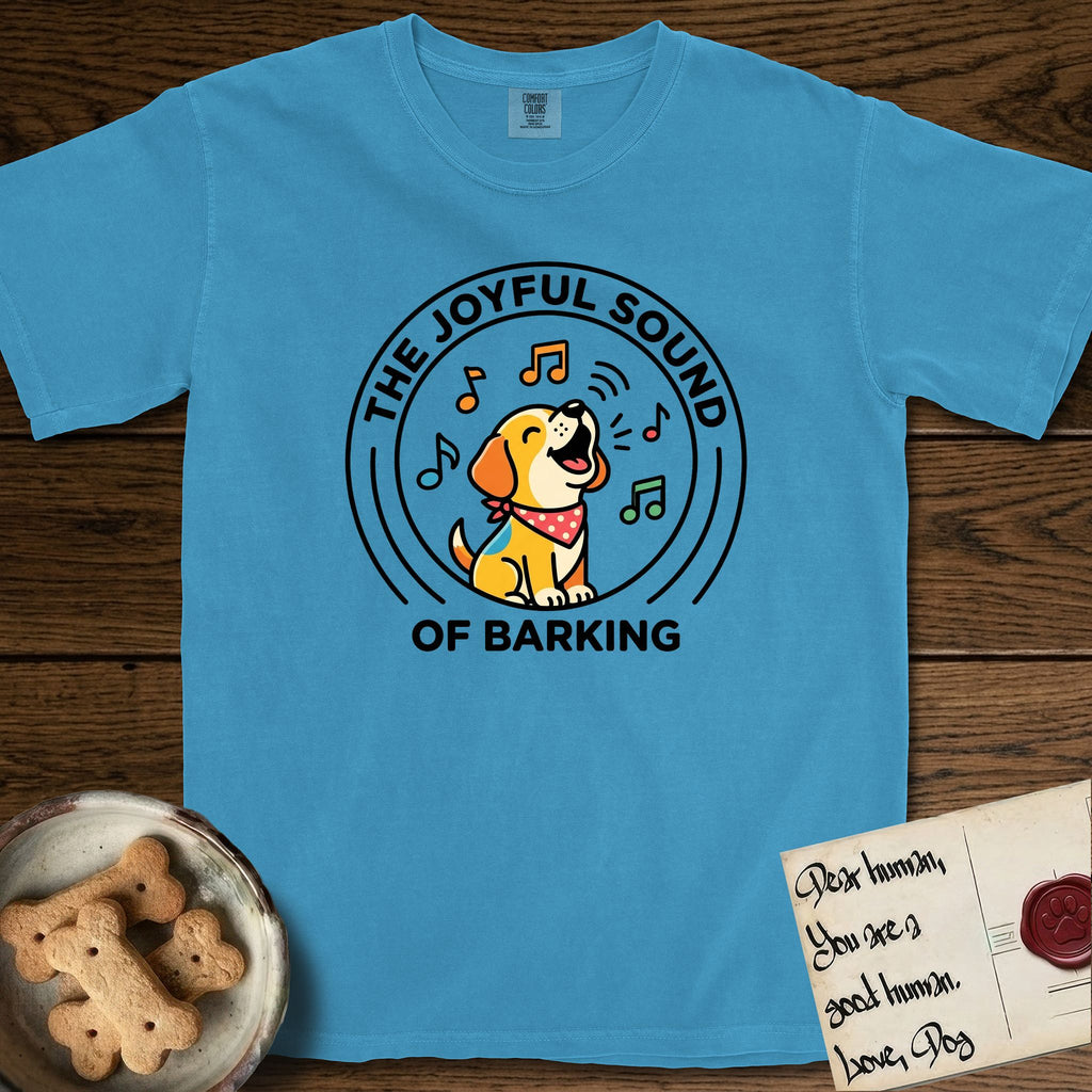 The Joyful Sound of Barking T-Shirt flat lay in Royal Caribe, featuring a flat vector cartoon emblem of a happy puppy with lifted ears surrounded by musical notes, ringed by the words The Joyful Sound of Barking.