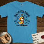 The Joyful Sound of Barking T-Shirt flat lay in Royal Caribe, featuring a flat vector cartoon emblem of a happy puppy with lifted ears surrounded by musical notes, ringed by the words The Joyful Sound of Barking.