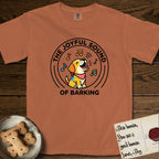 The Joyful Sound of Barking T-Shirt flat lay in Yam, featuring a flat vector cartoon emblem of a happy puppy with lifted ears surrounded by musical notes, ringed by the words The Joyful Sound of Barking.