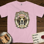 What Would Dog Do Beagle T-Shirt flat lay in Blossom, featuring a baroque scrollwork gold portrait medallion of a haloed Beagle with the question What Would Dog Do.