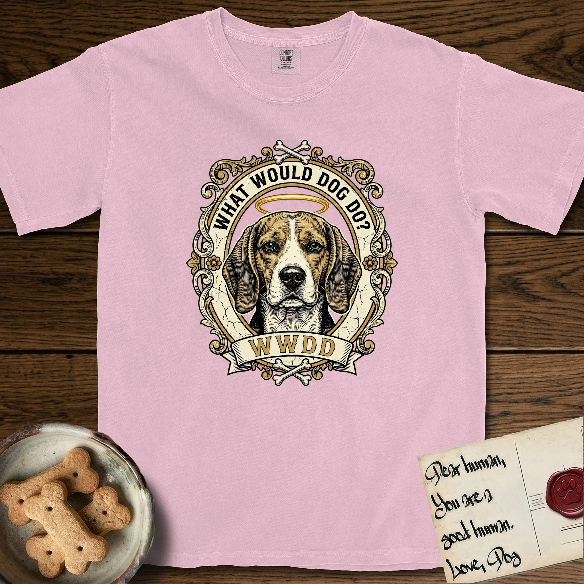 What Would Dog Do Beagle T-Shirt flat lay in Blossom, featuring a baroque scrollwork gold portrait medallion of a haloed Beagle with the question What Would Dog Do.