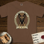 What Would Dog Do Belgian Malinois T-Shirt flat lay in Espresso, featuring a vintage gold portrait medallion of a haloed Belgian Malinois in an ornamental rosette-scroll border with the question What Would Dog Do.