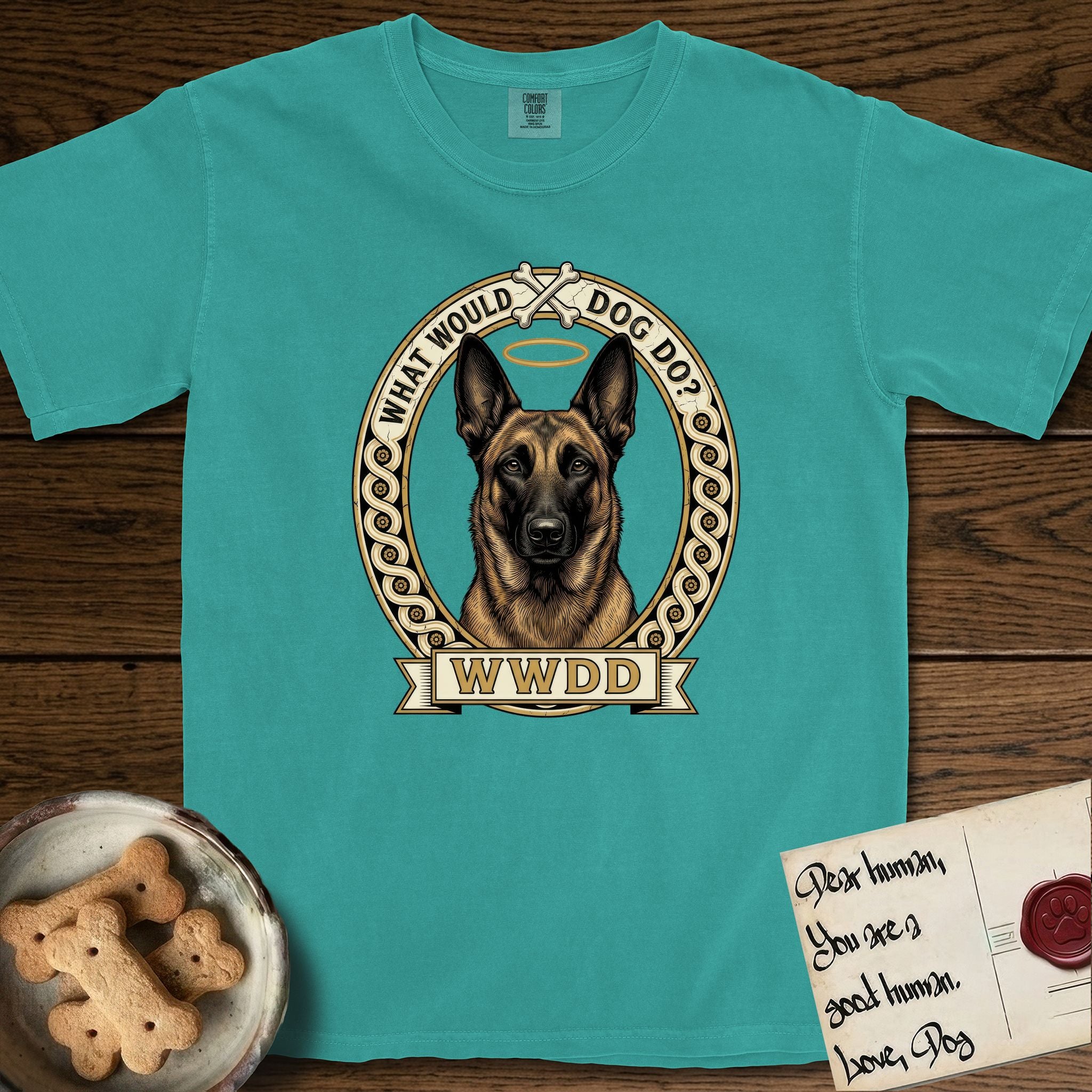 What Would Dog Do Belgian Malinois T-Shirt flat lay in Seafoam, featuring a vintage gold portrait medallion of a haloed Belgian Malinois in an ornamental rosette-scroll border with the question What Would Dog Do.