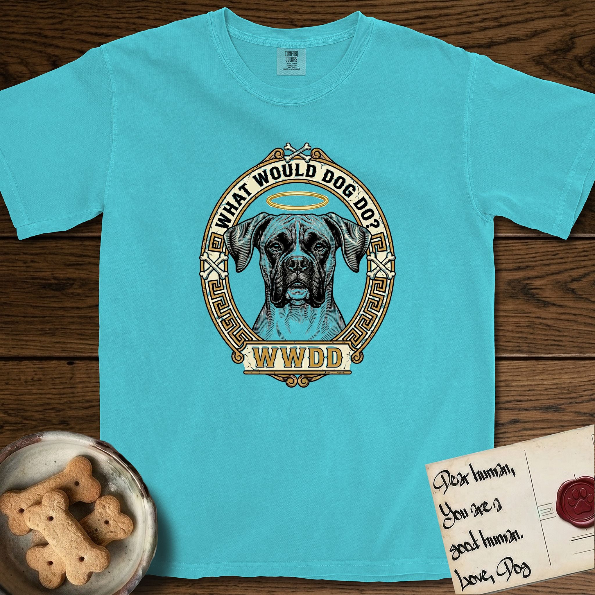 What Would Dog Do Boxer T-Shirt flat lay in Lagoon Blue, featuring a Greek-key bordered gold portrait medallion of a haloed Boxer with natural uncropped ears and the question What Would Dog Do.