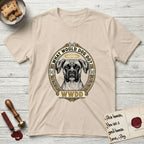 What Would Dog Do Boxer T-Shirt flat lay in Sand, featuring a Greek-key bordered gold portrait medallion of a haloed Boxer with natural uncropped ears and the question What Would Dog Do.